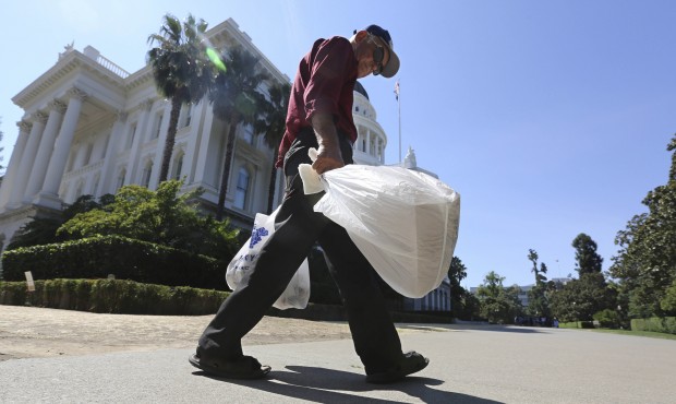 In this Aug. 12, 2014 file photo, a man carries plastic single-use bags past the State Capitol in S...