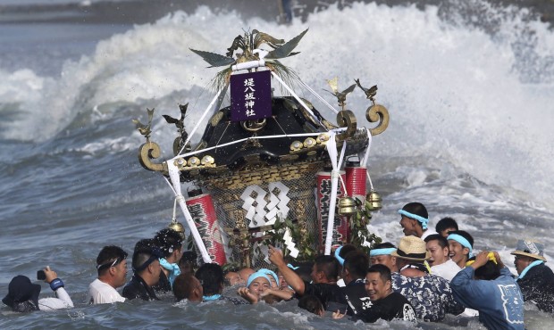 Participants carry a portable shrine, or mikoshi, into the sea during a purification rite at the an...