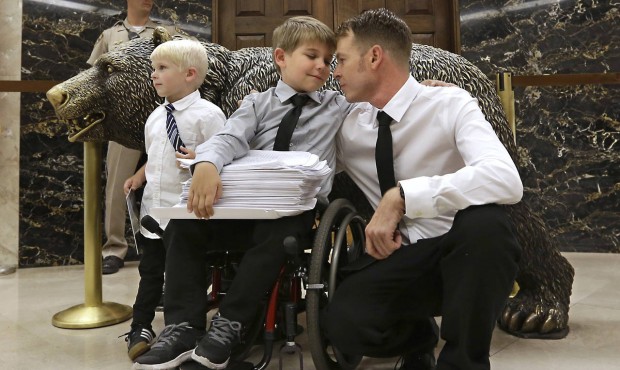 Otto Coleman, 6, waits outside the Governor’s office with his brother Fenton, 4, left, and fa...