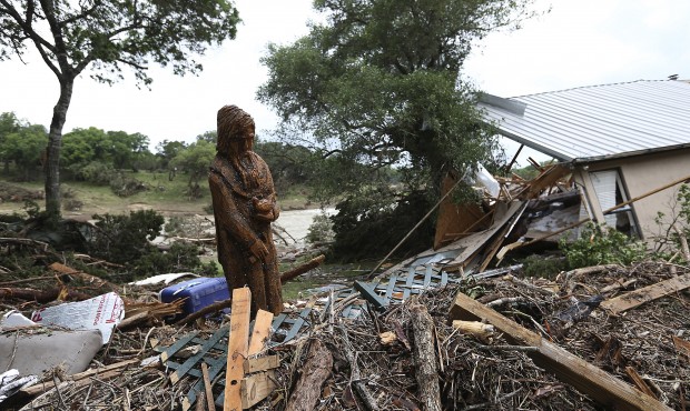 A carving of St. Francis of Assisi stands amid debris next to a destroyed home on River Road in Wim...