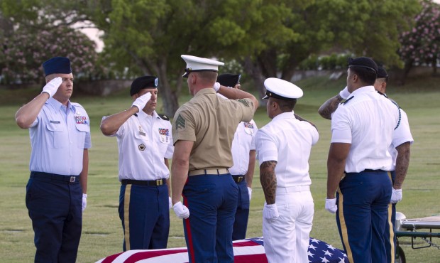 Military pallbearer salute the exhumed remains of unidentified crew members of the USS Oklahoma kil...