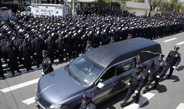 Police officers salute as the procession for New York City Police officer Brian Moore passes after ...