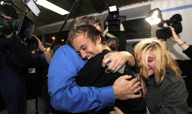 In this Saturday, Nov. 26, 2011, file photo, Derrik Sweeney, center, receives hugs from his father ...