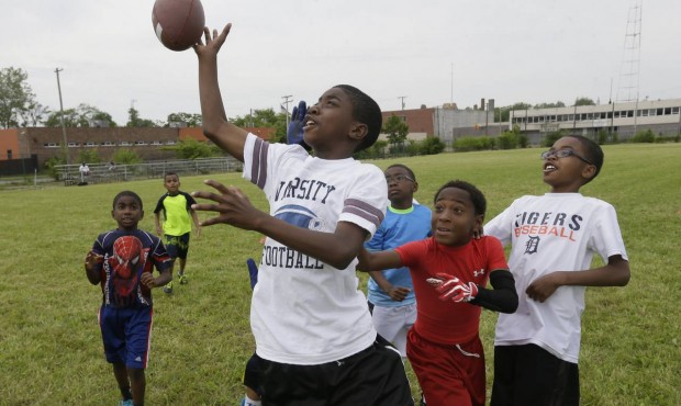 In this photo taken June 17, 2015, kids play football in McKenzie Field in Highland Park, Mich. For...