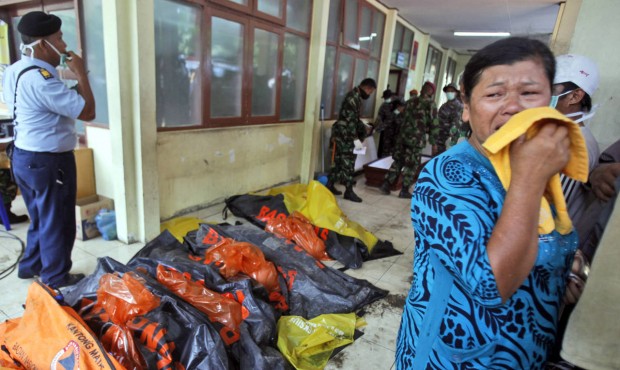 A relative weeps near body bags containing the remains of the victims of a military cargo plane tha...