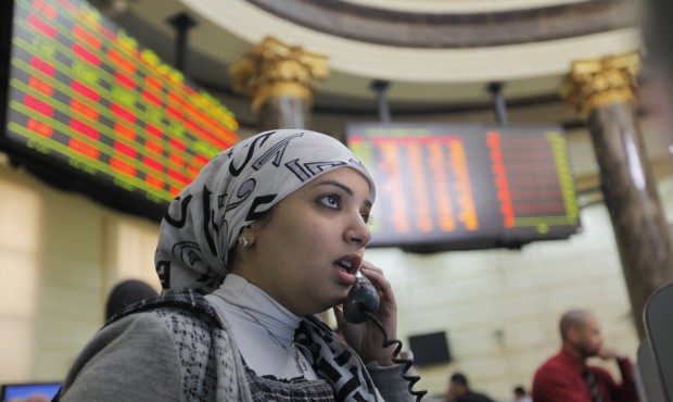FILE – In this March 10, 2013 file photo, an Egyptian trader talks as she monitors her screen...