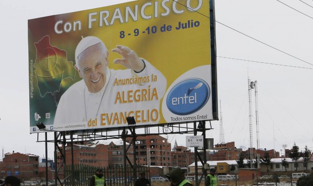 Police stand guard near a billboard of Pope Francis covered by the Spanish words: “With Franc...