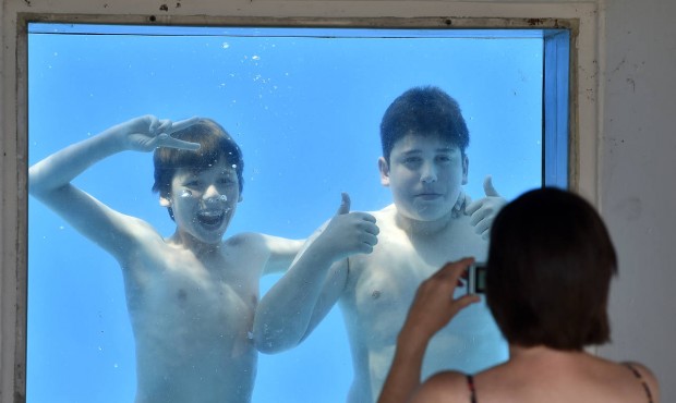 Julian, left, is photographed by his mother with friend Gianluca, right, under water at a public po...