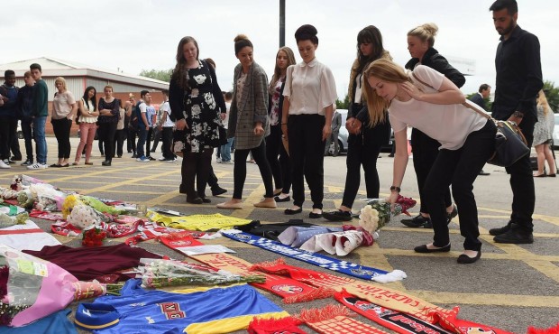 People lay flowers and scarves in tribute to three club soccer fans who lost their lives in the rec...