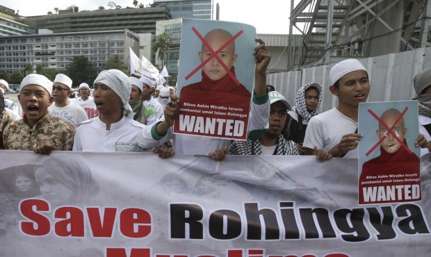 Indonesian Muslim protesters hold defaced posters of Myanmar’s radical Buddhist monk Ashin Wi...