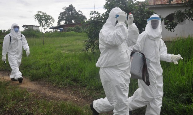 Health workers leave after they took a blood specimen from a child to test for the Ebola virus in a...