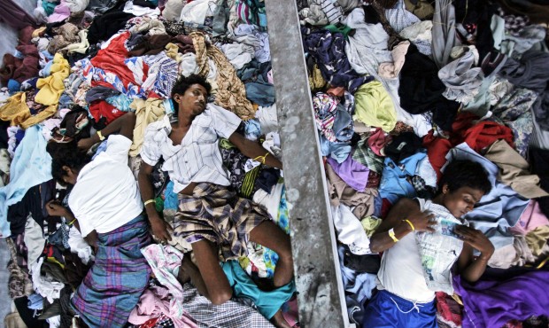 Ethnic Rohingya men take a nap on a pile of clothes donated by local residents at a temporary shelt...