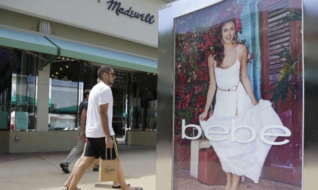 FILE – In this March 13, 2015 file photo, shoppers walk past an advertisement for retailer &#...