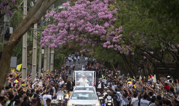 People line the street where Pope Francis passes in his popemobile as he makes his way to the Leon ...