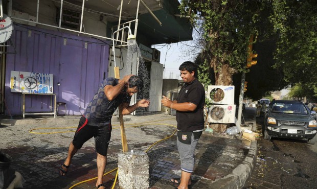 People cool themselves with water in central Baghdad, Iraq, Thursday, July 16, 2015. The government...