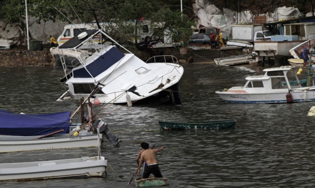 Two men paddle on a small boat towards a yatch that was damaged by winds and rains from hurricane C...
