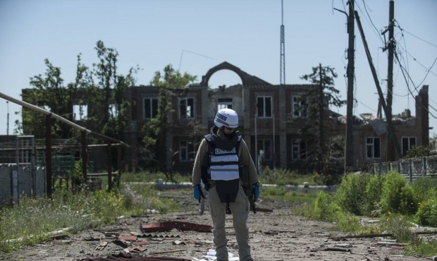 An OSCE monitor checks the territory for mines during a patrol in Shyrokyne, Donetsk region eastern...