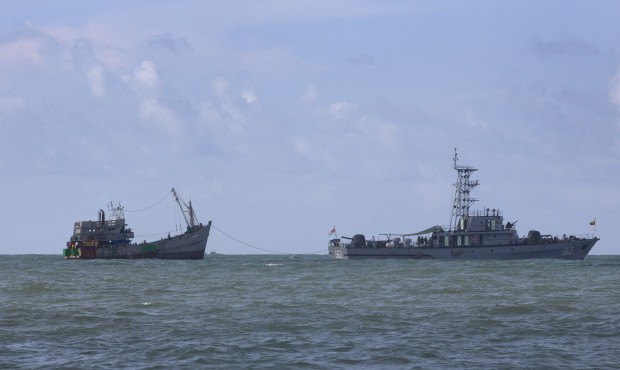 A Myanmar navy boat, with migrants-onboard, tows a boat with migrants off Myanmar’s Thameehla...