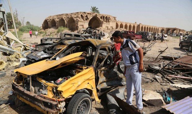 Civilians inspect the aftermath of a suicide car bombing at a busy market in Khan Bani Saad in the ...