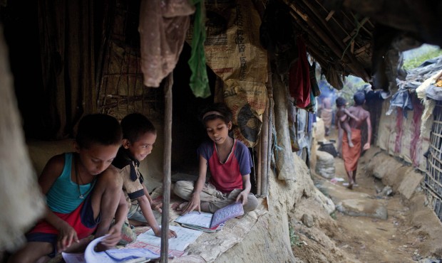 In this Thursday, May 21, 2015 photo, children read books inside their makeshift tent at a camp for...