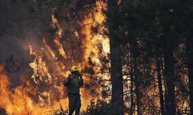 FILE – In this Aug. 25, 2013 file photo, firefighter A.J. Tevis watches the flames of the Rim...