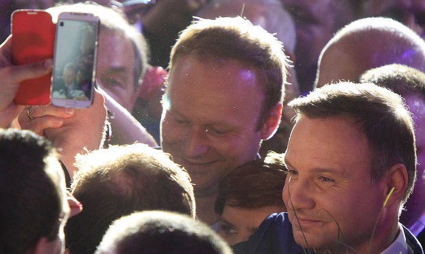 Opposition candidate Andrzej Duda, right, celebrates with supporters his victory, as first exit pol...