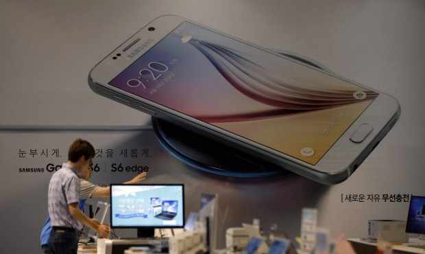 Employees of Samsung Electronics Co. check the products near an advertisement of Samsung Electronic...