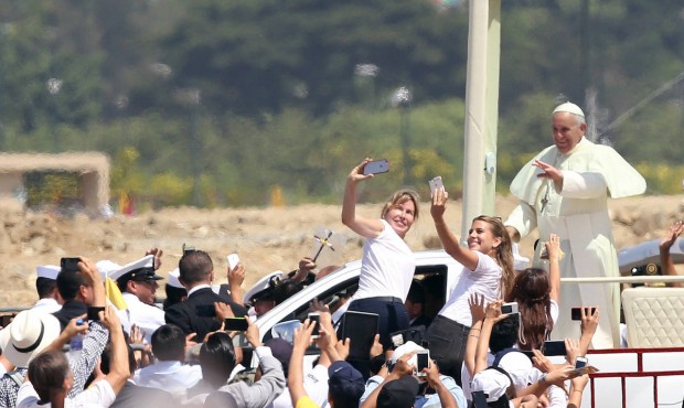 Pope Francis waves to the crowd as he rides in the popemobile through Samanes Park, where he will c...
