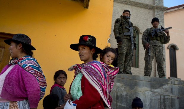 Villagers watch a welcome ceremony for visiting military as soldiers stand guard in Surcubamba, Per...