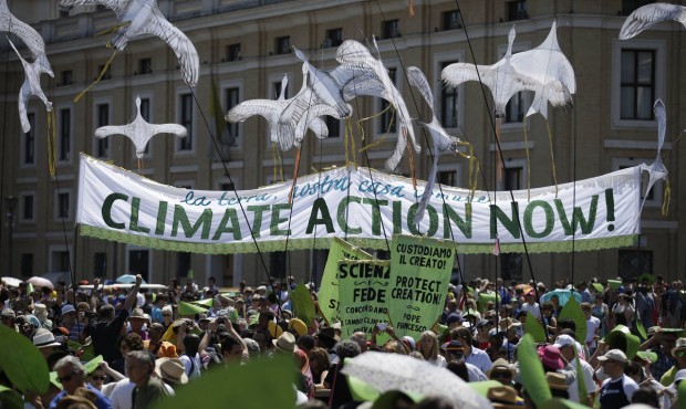 People hold a banner reading ‘ Climate action Now ‘ in St. Peter’s Square, at the...