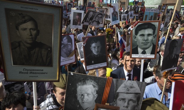Local residents march as they carry portraits of relatives who fought in World War II, in central M...