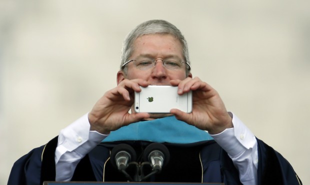 Apple CEO Tim Cook takes a picture with his iPhone while addressing graduates during George Washing...