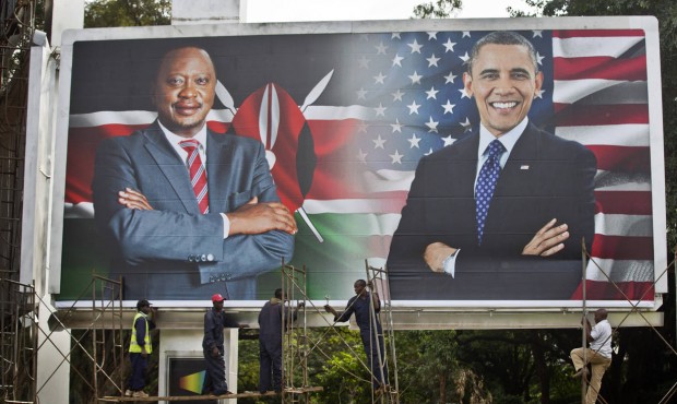 Workers finish installing a large billboard showing Kenya’s President Uhuru Kenyatta, left, a...
