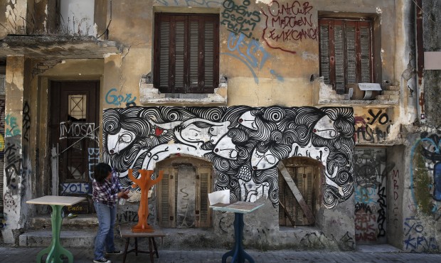 A woman paints tables before going on sale at her shop in Athens, Greece, on Monday, May 4, 2015. W...