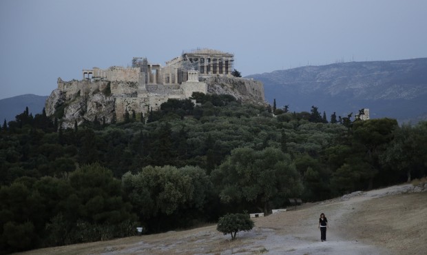 A woman walks on Pnyx hill in front of the ancient Acropolis of Athens, on Wednesday, May 6, 2015. ...