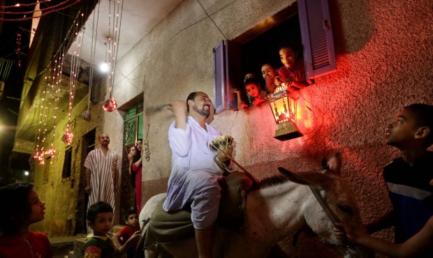 In this Friday, July 10, 2015 photo, a girl hold a traditional lantern as Essam Sayed, the 45-year-...