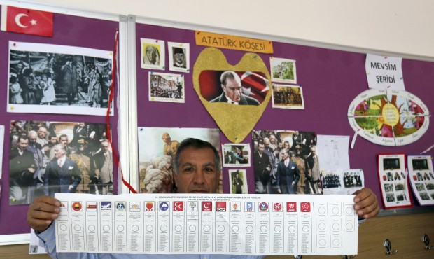 A polling station official shows a ballot paper with the names of political parties participating i...