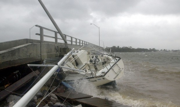 FILE – In this Sept. 16, 2004 file photo, waves crash against a sailboat lodged under a bridg...