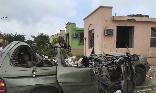 People stand near a destroyed vehicle after a powerful tornado swept past in Ciudad Acuna, northern...