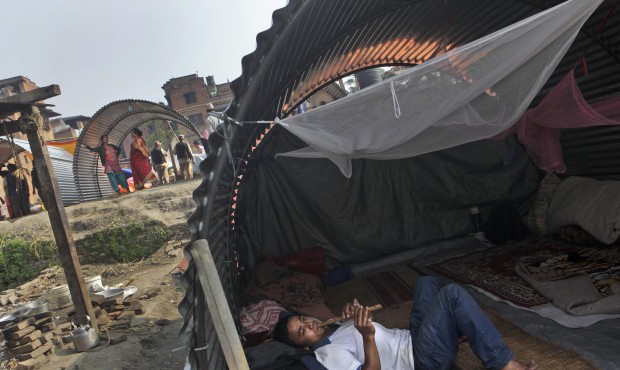 A Nepalese man, whose house was damaged in the April 25 earthquake, plays a flute in a temporary sh...