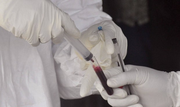 Health workers take a blood specimen from a child to test for the Ebola virus in a area were a 17-y...