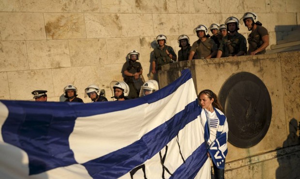 n Supporters of the NO vote in the upcoming referendum hold a Greek flag as riot police block the e...