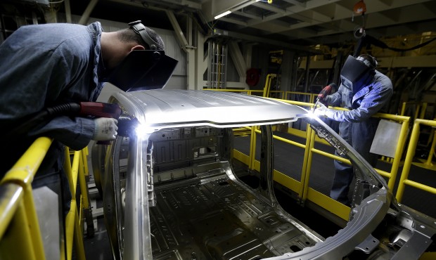 In this March 13, 2015 photo, workers weld body panels on the new aluminum-alloy body Ford F-150 tr...