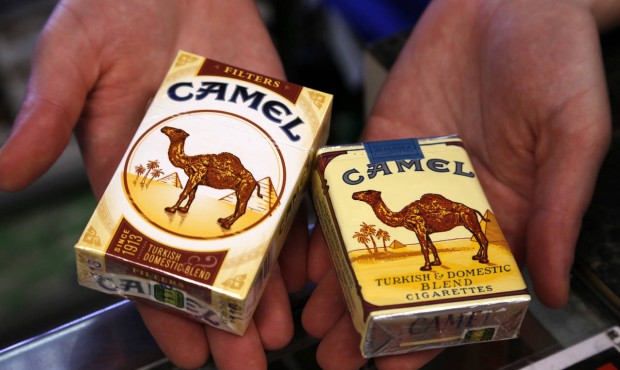In this July 17, 2015 photo, store manager Stephanie Hunt poses for photos with packs of Camel ciga...
