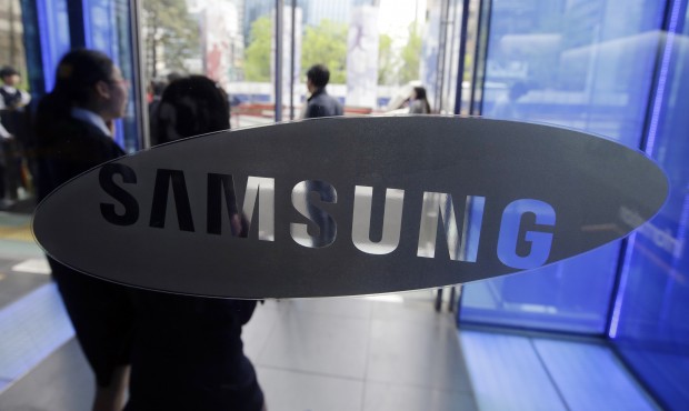 FILE – In this April 29, 2015 file photo, visitors walk by the logo of Samsung Electronics Co...
