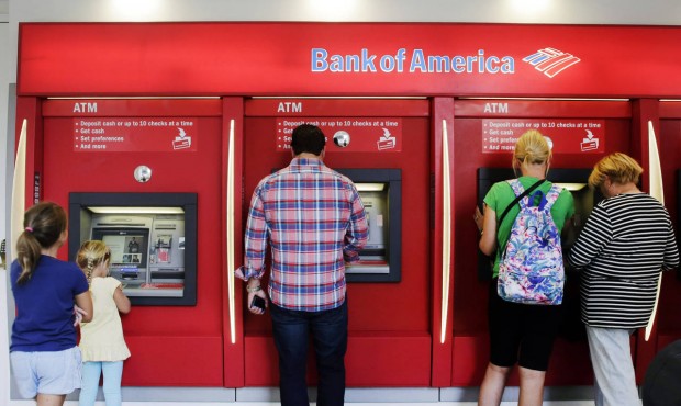 In this photo taken, Monday, July 13, 2015, customers use ATMs at a branch office of Bank of Americ...
