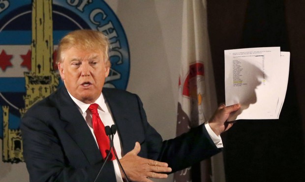 Republican presidential candidate Donald Trump casts a shadow against papers he used while speaking...