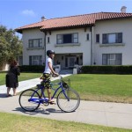 A young boy rides his bike past the Spreckels Mansion as a woman takes a photo in Coronado, Calif. Monday, July 18, 2011. The mansion is the site where a woman was found dead last week, hanging nude from a balcony with her hands and feet bound. (AP Photo/Lenny Ignelzi)