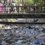A boy tries to climb back to a foot bridge after searching for a ball in a canal which is choked by non-bio-degradable garbage in Mumbai, India, Monday, April 22, 2013. April 22 is observed as Earth Day every year as a tool to raise ecological awareness. (AP Photo/Rafiq Maqbool)
