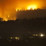 In this Tuesday, June 7, 2011 photo, flames from the Wallow Fire burn near homes in Eagar, Ariz. A raging forest fire in eastern Arizona has scorched an area the size of Phoenix, threatening thousands of residents and emptying towns as the flames raced toward New Mexico. (AP Photo/The Arizona Republic, Michael Chow)